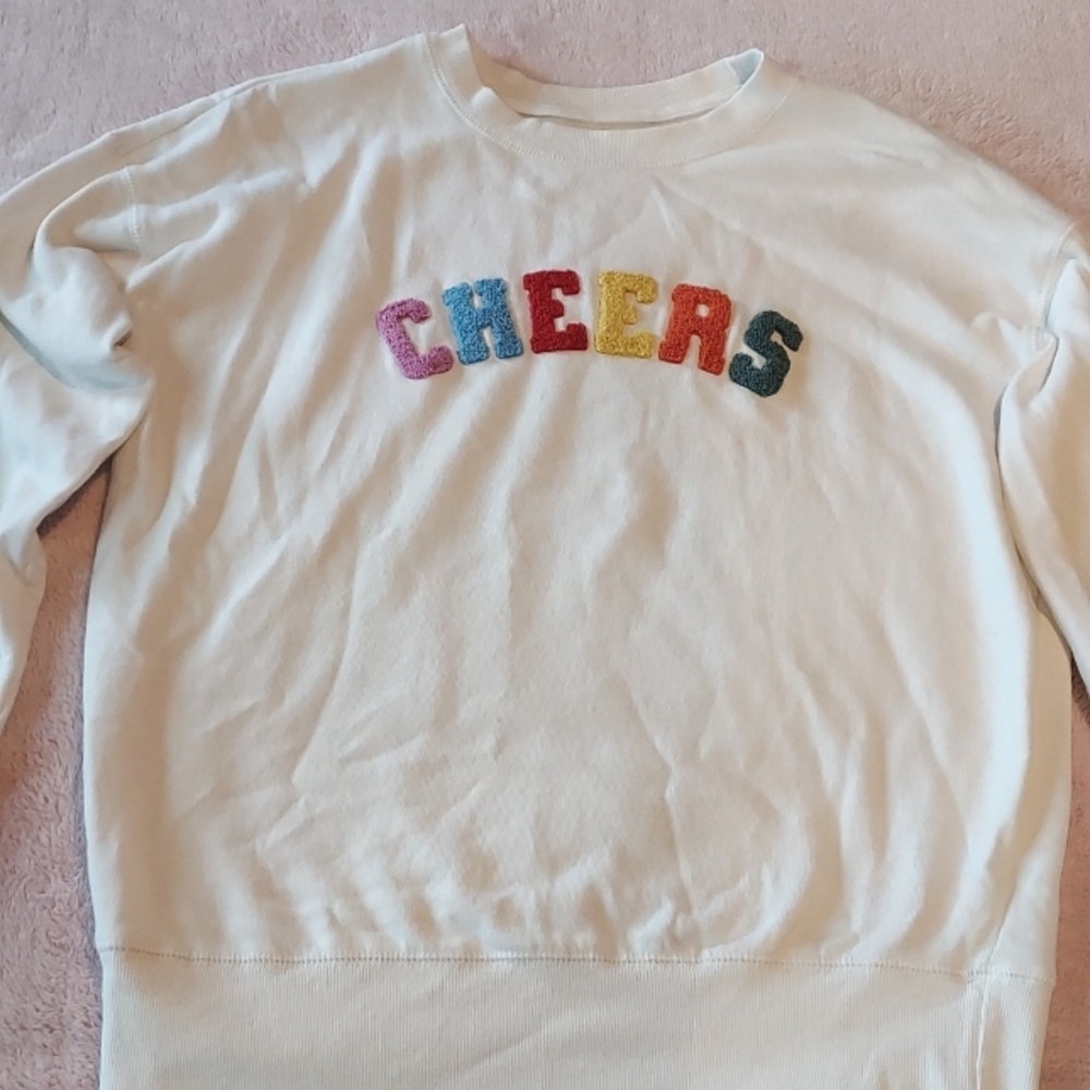 A white sweater with "Cheers" in bright, beautiful colors.